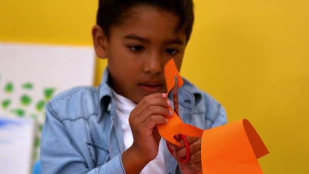 Garçon découpe des formes de papier en classe — Video