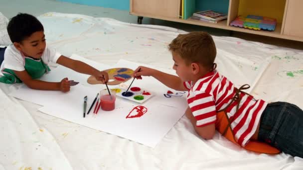 Мальчики рисуют лежа на бумаге в классе — стоковое видео