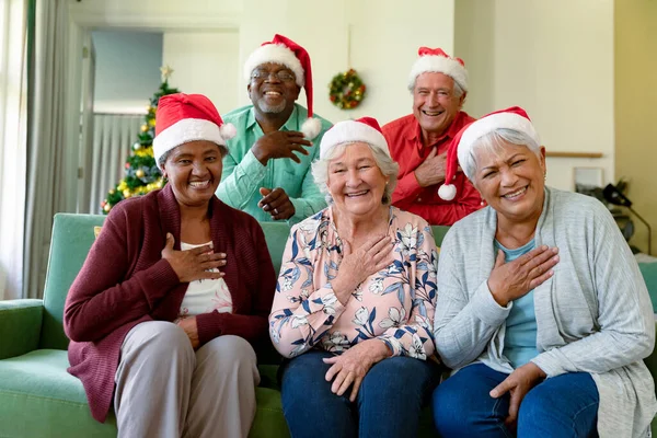 クリスマスの時間にビデオ通話を持つサンタの帽子のシニア友人の幸せな多様なグループのグループ クリスマスやお祭りや通信技術は — ストック写真