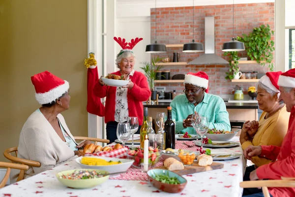 休日の帽子の幸せなシニア友人の多様なグループが自宅で一緒にクリスマスを祝う クリスマスのお祝い友達と家でお祝いする — ストック写真