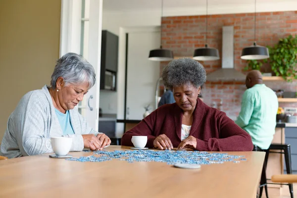 Dos Amigas Diversas Sentadas Cocina Con Café Haciendo Rompecabezas Socializar —  Fotos de Stock