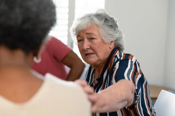 白人老年妇女触摸非洲裔美国女性朋友并支持她 老年人的健康 支助和生活方式 — 图库照片