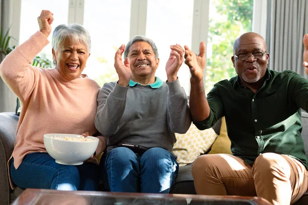 两只快乐多样的老夫妇和他们的非洲裔美国男性朋友一起看电视 玩得很开心 退休后的生活方式随着科技的进步而放松 — 图库照片