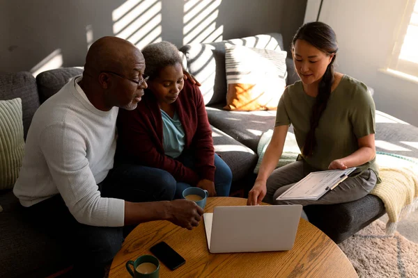 アフリカ系アメリカ人のシニアカップルは 自宅でアジア系女性の財務顧問と会っている 退職生活や高齢者への支援や家庭での時間を — ストック写真