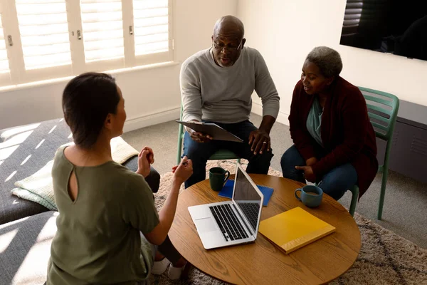 African american senior couple having meeting with asian female financial advisor at home. retirement lifestyle, elderly support and spending time at home.