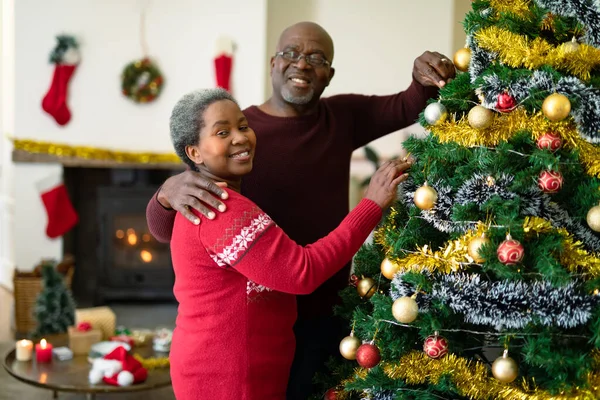 クリスマスツリーを飾る幸せなアフリカ系アメリカ人のシニアカップル 引退生活やクリスマスのお祭りを自宅で祝い — ストック写真