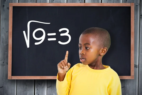 Boy pointing against blackboard — Stock Photo, Image