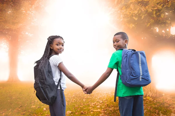Pupils holding hands against trees — Stock Photo, Image