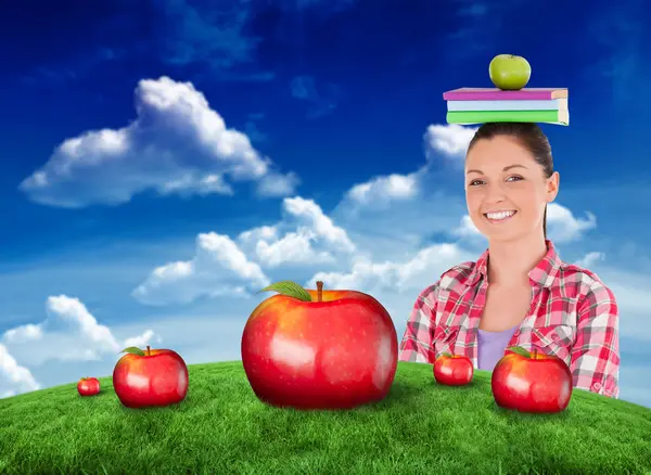 Estudiante sosteniendo una manzana y libros en la cabeza — Foto de Stock