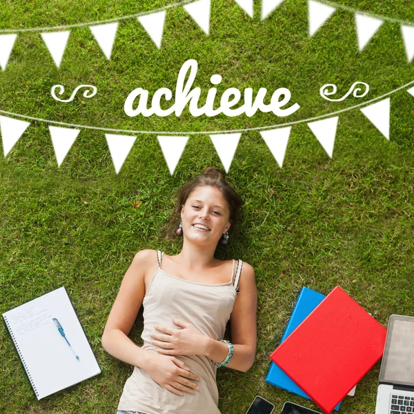 Achieve against pretty student lying on grass — Stock Photo, Image