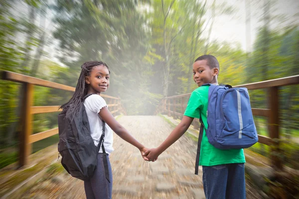 Pupils holding hands against bridge — Stock Photo, Image