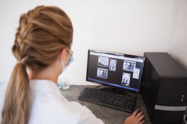 Dental assistant looking at x-rays on computer clipart