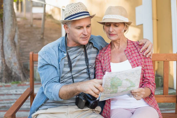 Glückliches Touristenpaar schaut auf Landkarte auf einer Bank in der Stadt — Stockfoto