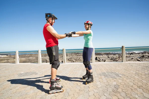 Fit mature couple rollerblading on the pier — Stock Photo, Image