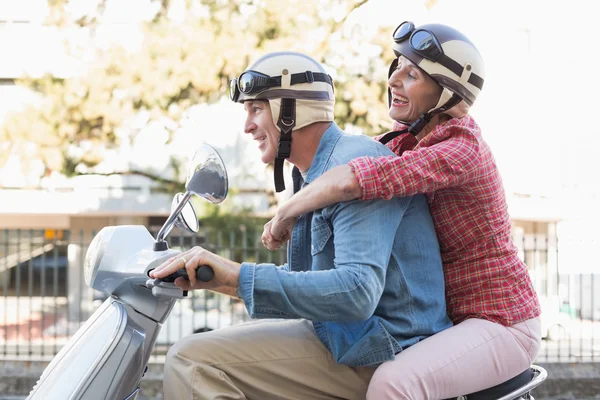 Pasangan yang bahagia dan dewasa mengendarai skuter di kota — Stok Foto