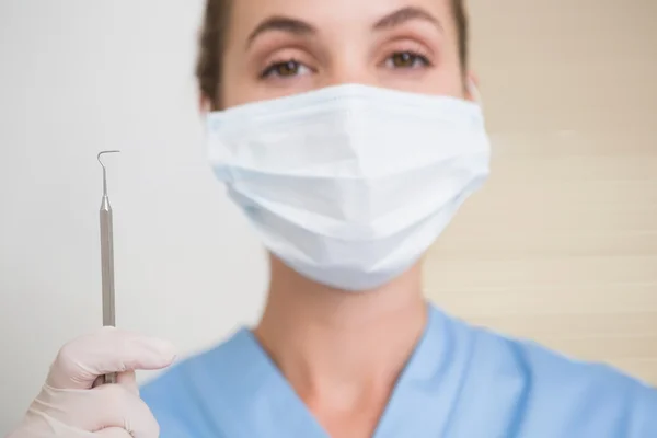 Dentist in surgical mask holding dental explorer — Stock Photo, Image
