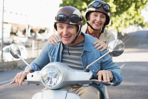 Happy mature couple riding a scooter in the city — Stock Photo, Image