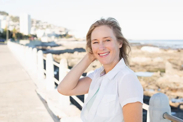 Femme décontractée souriant à la caméra près de la mer — Photo