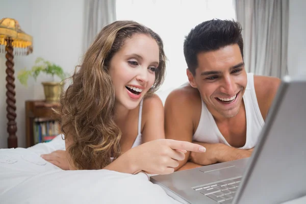 Casal alegre usando laptop na cama em casa — Fotografia de Stock