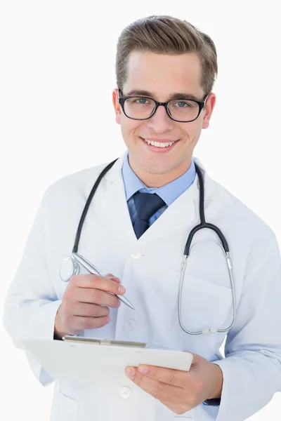 Sorrindo jovem médico escrevendo na área de transferência — Fotografia de Stock