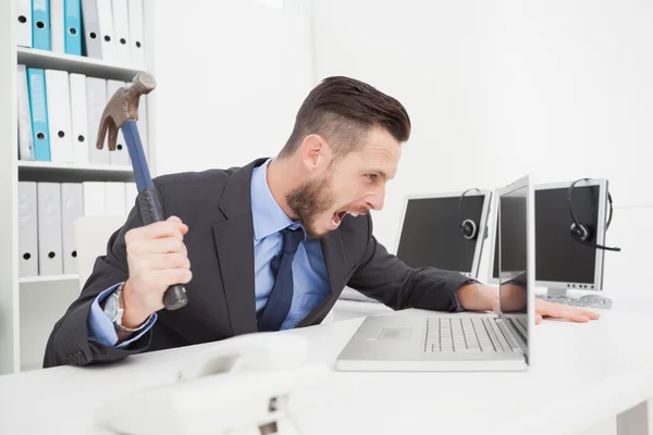 Angry businessman holding hammer over laptop — Stock Photo, Image