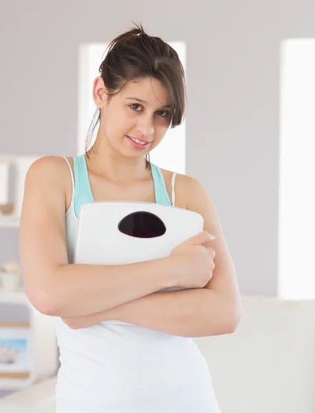 Fit brunette smiling at camera holding scales — Stock Photo, Image