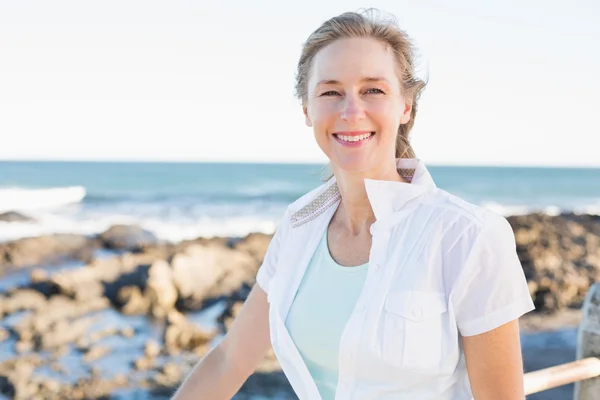 Femme décontractée souriant à la caméra près de la mer — Photo