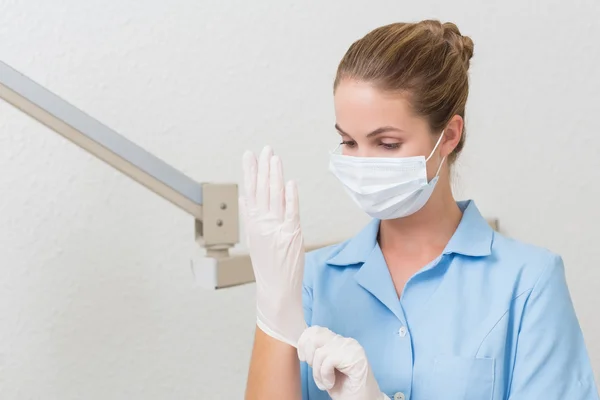 Zahnarzthelferin in Maske zieht Handschuhe an — Stockfoto