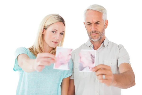 Unhappy couple holding two halves of torn photograph — Stock Photo, Image