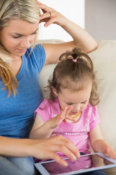 Mother and daughter using digital tablet on couch — Stock Photo, Image