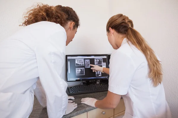 Dentista y asistente estudiando rayos X en la computadora —  Fotos de Stock