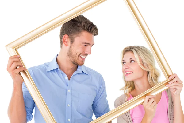 Attractive young couple holding picture frame — Stock Photo, Image