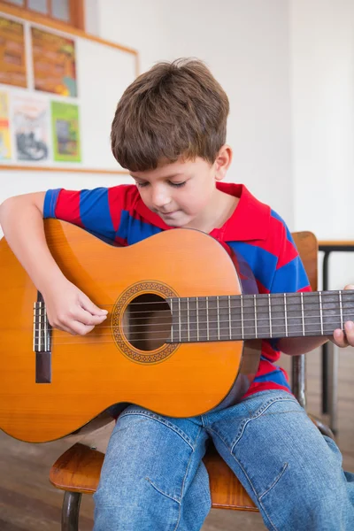 Pupil playing guitar in classroom — Stock Photo, Image
