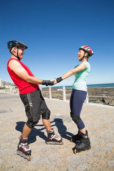 Fit mature couple rollerblading on the pier — Stock Photo, Image