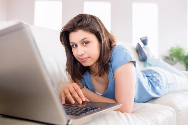Půvabná brunetka pomocí přenosného počítače na gauči — Stock fotografie