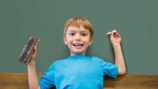 Pupil holding chalk and duster in classroom — Stock Photo, Image