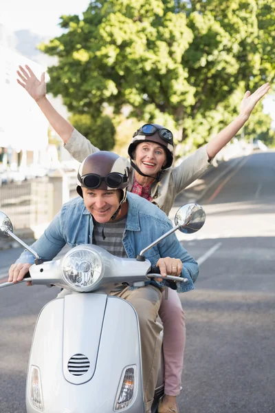 Happy mature couple riding a scooter in the city — Stock Photo, Image