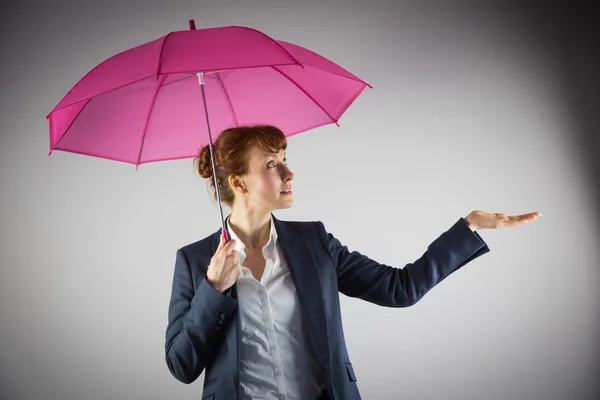 Smiling businesswoman holding pink umbrella — Stock Photo, Image