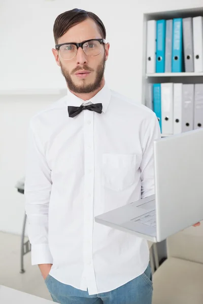 Nerdy businessman holding laptop looking at camera — Stock Photo, Image