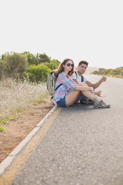 Couple hitchhiking on countryside road — Stock Photo, Image