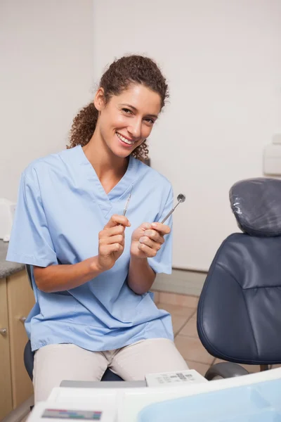 Dentist in blue scrubs holding tools — Stock Photo, Image