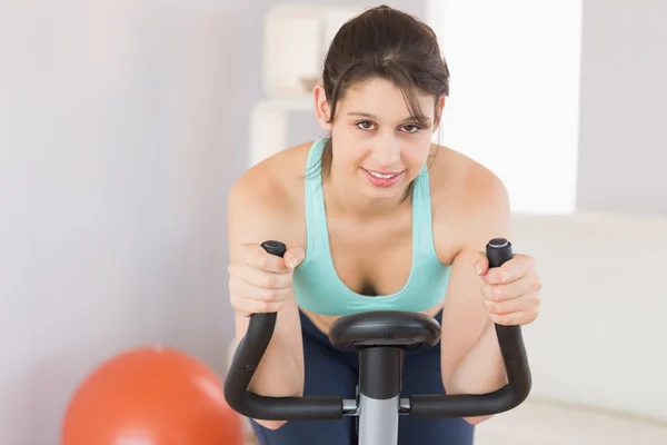 Passen brunette trainen op de hometrainer — Stockfoto