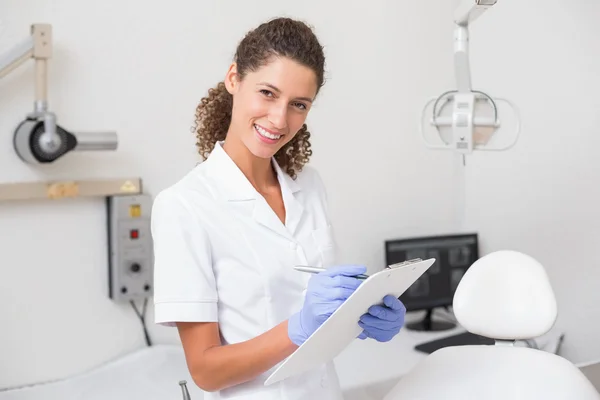 Dental assistant writing in clipboard — Stock Photo, Image