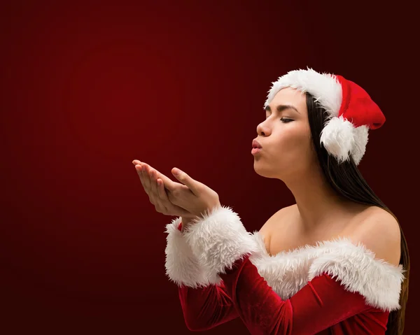 Morena en traje de santa soplando sobre las manos —  Fotos de Stock