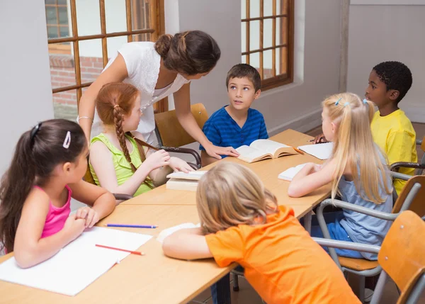 Teacher standing with pupils at desk — Stock Photo, Image