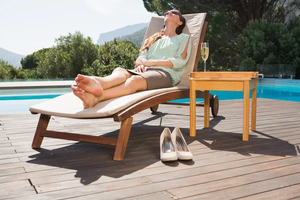 Frau entspannt sich auf Liegestühlen am Pool — Stockfoto