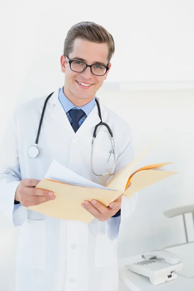 Smiling young doctor writing on clipboard — Stock Photo, Image