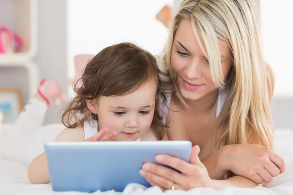 Madre e hija joven tableta digital en la cama —  Fotos de Stock