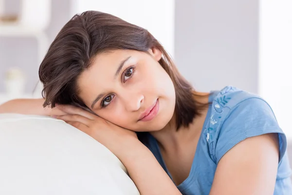 Pretty brunette smiling at camera on the couch — Stock Photo, Image