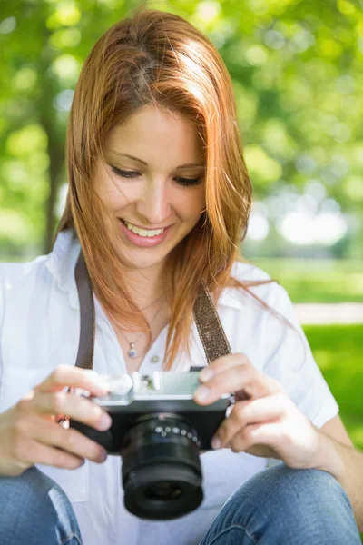 Redhead kijken naar haar camera in het park — Stockfoto